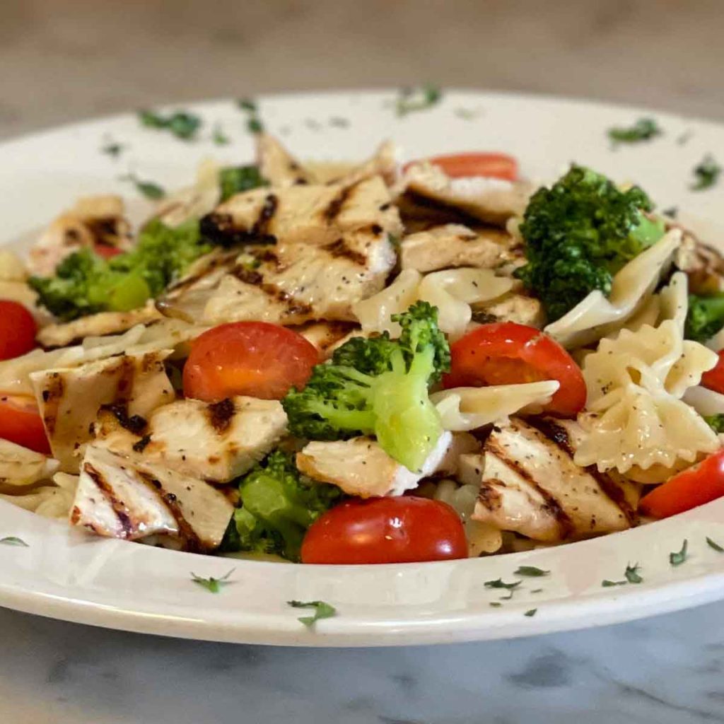 Grilled chicken with broccoli and tomatoes over bowtie pasta